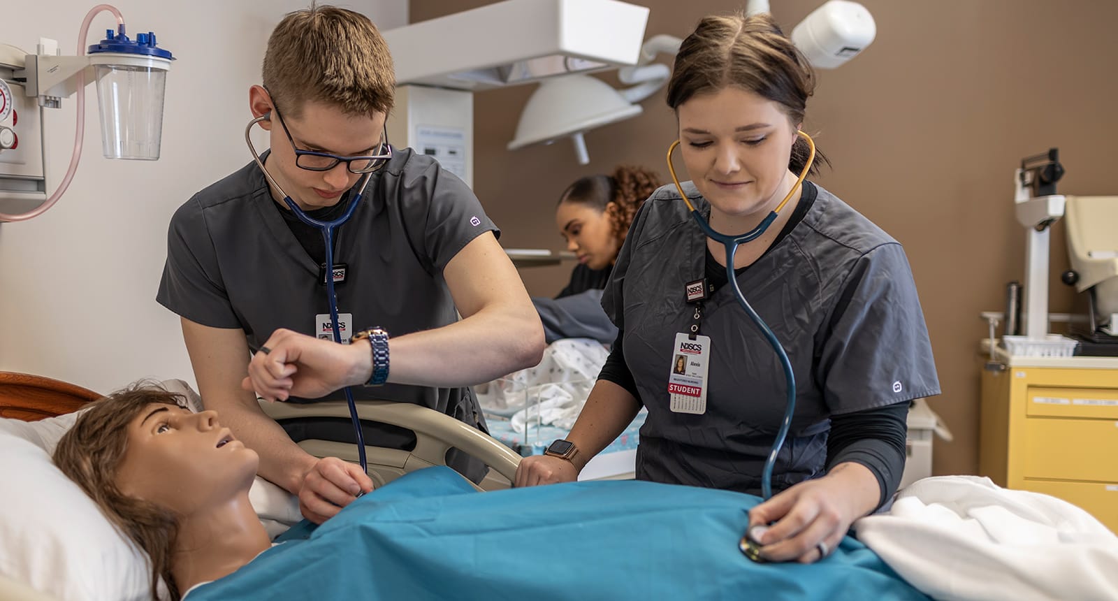 Nursing students practicing patient care with a medical mannequin in a clinical lab setting