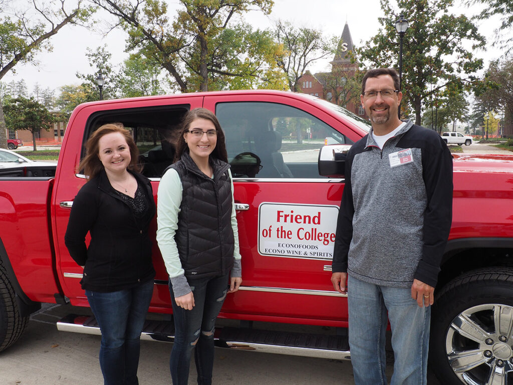 Econofoods team in front of a red truck with a Friend of the College sign on the door.